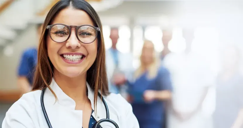 Family nurse practitioner with DNP smiling with medical team in background